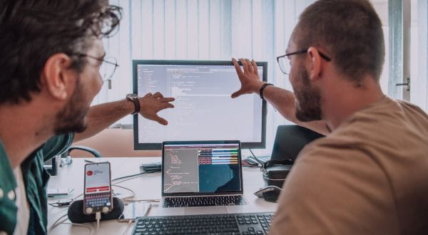 Developers wijzen naar scherm met code erop